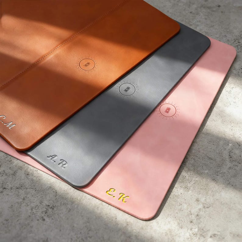 K&ouml;nnte beinhalten: Drei Schreibtischunterlagen aus Leder in Braun-, Grau- und Rosat&ouml;nen. Jede Unterlage hat ein kreisf&ouml;rmiges gepr&auml;gtes Design und personalisierte Initialen. Die Unterlagen sind rechteckig und scheinen aus hochwertigem Leder zu sein.