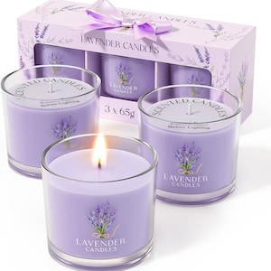 May include: Three lavender-scented candles in clear glass holders, one lit with a flame. The candles are labeled "LAVENDER CANDLES" and come in a box with a lavender bow. Each candle is 65g.