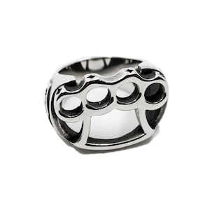 Op de afbeelding: Een zilveren ring met een knokkelstoot-ontwerp. De ring is gemaakt van metaal en heeft een gladde afwerking.