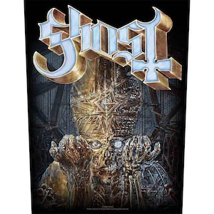 May include: A black graphic featuring the band name "Ghost" in a light blue and gold 3D font. The image depicts a skeletal figure with a gold and bronze face and hands, set against a dark, architectural background.