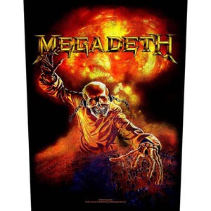 Peut inclure: Graphique noir avec le nom du groupe "MEGADETH" en lettres dorées au-dessus d'une figure squelettique avec des chaînes, sur fond orange et rouge flamboyant. La figure tend les mains osseuses.