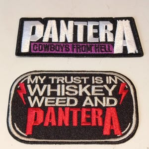 Puede incluir: Dos parches bordados. El parche superior dice "PANTERA COWBOYS FROM HELL" en blanco y morado sobre un fondo negro. El parche inferior dice "MY TRUST IS IN WHISKEY WEED AND PANTERA" en rojo y blanco sobre un fondo negro.