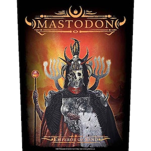 May include: A black and red graphic featuring the band name "MASTODON" above an illustration of a skeletal figure in ornate armor, holding a staff. The text "EMPEROR OF SAND" is below the figure.