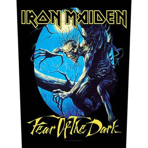 Könnte beinhalten: Schwarzer Aufnäher mit dem gelben Iron Maiden-Logo. Darunter eine blau-schwarze Illustration einer skelettartigen Figur mit bedrohlichem Ausdruck. Der Text "Fear of the Dark" ist gelb dargestellt.