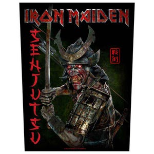 Puede incluir: Gráfico negro con el logotipo de la banda Iron Maiden y un guerrero samurái con ojos rojos brillantes, empuñando una espada. Texto japonés a la izquierda y un sello rojo a la derecha.