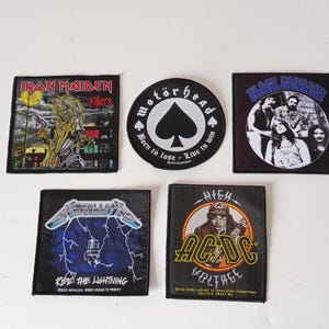 May include: Collection of six fabric patches featuring iconic rock band logos. Includes Iron Maiden, Motörhead, Black Sabbath, Metallica, and AC/DC. Each patch has a unique design and color scheme, perfect for jackets or bags.