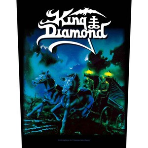May include: Black graphic featuring the band King Diamond. The image depicts a horse-drawn carriage with two horses in front, set against a dark, atmospheric backdrop with the band's logo in white.