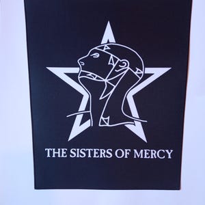 May include: Black and white patch featuring a stylised image of a head within a five-pointed star. The text "THE SISTERS OF MERCY" is positioned beneath the star.
