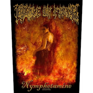 Op de afbeelding: Een zwarte en gouden patch met de bandnaam "Cradle of Filth" in een gestileerd lettertype. De patch toont een vrouw in een zwarte jurk die op een vurige oranje achtergrond staat. De tekst "Nymphetamine" is in een gestileerd lettertype onderaan de patch geschreven.