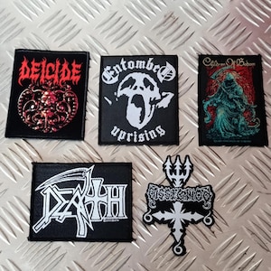 May include: Five black patches with white and red text and graphics. The patches feature the band names "Deicide", "Entombed", "Children of Bodom", "Death", and "Dissection". The patches are rectangular and cross-shaped.