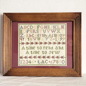 May include: A framed cross-stitch sampler with a wooden frame. The sampler features the alphabet, numbers, and the text "A time to rend and A time to sew." The colors include green, red, and brown.