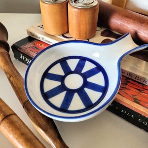 May include: A set of three ceramic mugs with a speckled, matte finish. Each mug features a different color: light blue, cream, and gray. The mugs have a simple, modern design with a rounded shape and a handle.