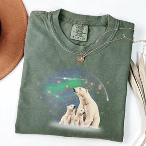 May include: Green t-shirt with a print of three polar bears looking up at the aurora borealis. The shirt has a tag that says "Comfort Colors" and "S - P - CH".