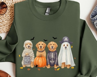 Może przedstawiać: Zielona bluza w kolorze wojskowym z czterema psami w kostiumach na Halloween. Jeden pies jest mumią z torbą "Trick or Treat". Inne są przebrane za dynię, szkielet i ducha. U góry znajduje się napis "MILITARY GREEN".