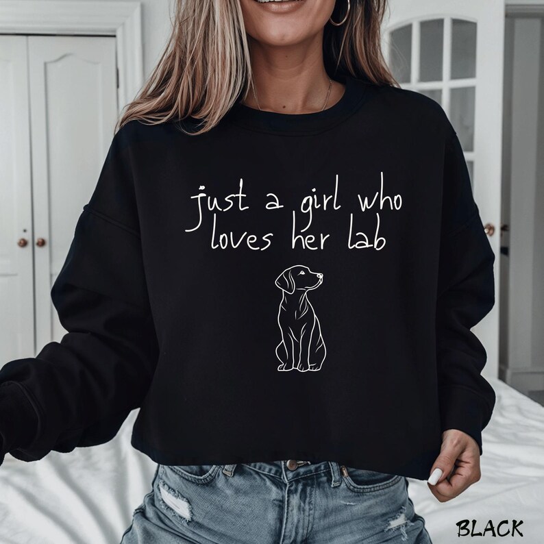 Puede incluir: Sudadera negra con la frase "just a girl who loves her lab" en fuente manuscrita. Un contorno blanco de un Labrador Retriever est&aacute; debajo del texto. La palabra "BLACK" est&aacute; en la esquina inferior derecha.