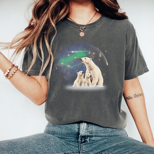May include: A dark gray t-shirt with a graphic of three polar bears looking up at a starry sky with a green aurora borealis. The bears are white and the sky is a dark blue with white stars.