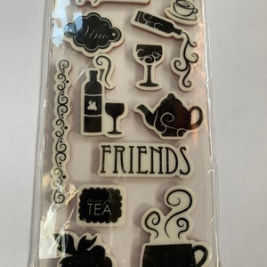 May include: A set of 11 repositionable rubber stamps with a white background and black ink. The stamps feature images of wine bottles, wine glasses, teacups, teapots, grapes, and the words "We're the perfect blend" and "Friends".