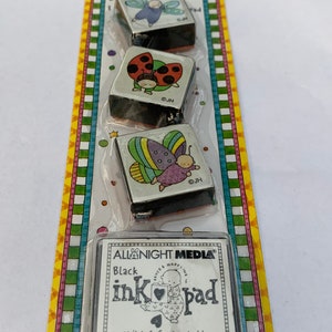 May include: A set of three rubber stamps featuring colorful illustrations of a butterfly, ladybug, and dragonfly. The stamps are packaged with a black ink pad labeled "All Night Media ink pad" and are child-safe, washable, and non-toxic.