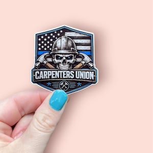 May include: A sticker featuring a skull wearing a hard hat, with crossed hammers and the text "CARPENTERS UNION." The design incorporates an American flag and a blue line, set within a shield shape. Held by a hand with a blue painted nail.