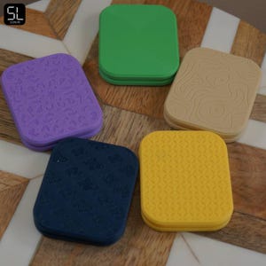 May include: A white ceramic mug with a black handle and the text "But First, Coffee" in a bold, black font. The mug is set against a blurred background, highlighting its simple design.