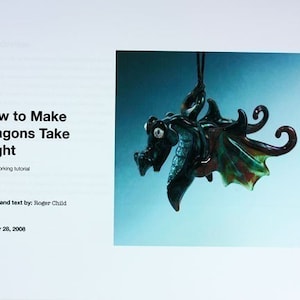 May include: A tutorial on how to make glass dragons, titled "How to Make Dragons Take Flight: A lampworking tutorial". The image shows a green glass dragon pendant with iridescent wings hanging from a cord against a light blue background. The text "October 28, 2008" and "Photos and text by: Roger Child" are also visible.