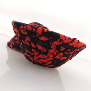 May include: A red and black fabric bowl with a woven pattern. The bowl is made of fabric scraps sewn together.
