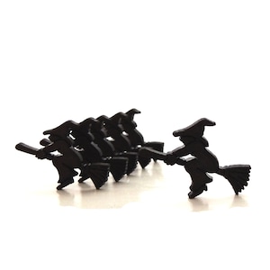 May include: A group of eight black silhouette witch figures on broomsticks. The witches are all facing the same direction and are flying in a line. The witch in the front is slightly ahead of the others.