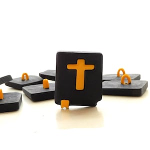May include: A close-up of a black and yellow button with a cross design. The button is surrounded by other buttons with different designs.