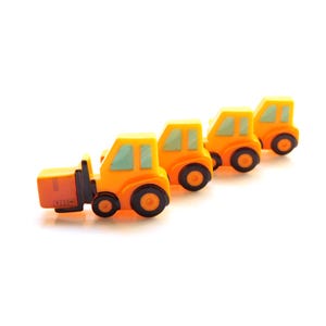 May include: Four yellow toy construction vehicles in a line. The vehicles have black wheels and blue windows. The first vehicle is a forklift with a brown cargo box.