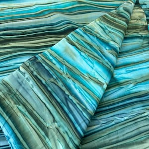 May include: A length of fabric featuring a horizontal, wavy, and layered pattern in shades of turquoise, teal, dark blue, and muted olive green. The design consists of fluid, irregular stripes that create a sense of depth and movement across the textile.