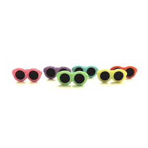 May include: Six pairs of glitter sunglasses in various colours, including pink, purple, green, yellow, and orange. The sunglasses are all the same style, with round lenses and a thin frame.