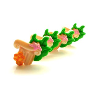 May include: A row of decorative miniature columns with a sea theme. Each column is tan with a green leaf design, a pink starfish, and a small orange flower. The columns are arranged diagonally on a white background.