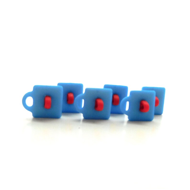 May include: Six small, light blue mugs with red accents. Each mug has a handle and a red detail on the front. The mugs are arranged in a slightly staggered pattern against a white background.