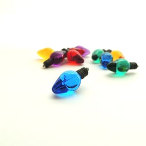 May include: Assortment of colorful miniature light bulbs, including blue, green, red, purple, and yellow. The bulbs are made of glass and have a metal wire attached to the bottom.