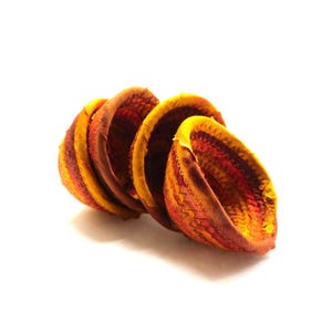 May include: A collection of handmade fabric bowls in yellow, orange, and red hues. The bowls feature a stitched, textured pattern and are arranged in a spiral. The design highlights the interior and exterior colours. The background is plain white.