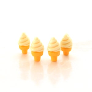 May include: Four miniature ice cream cones with a swirl of off-white ice cream on top of a yellow cone. The cones are arranged in a row against a white background. The image is well-lit and the colors are vibrant.