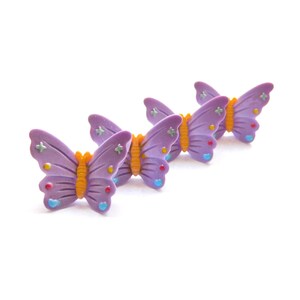 May include: Three purple butterfly-shaped buttons with colorful accents. The buttons have a 3D design and are perfect for adding a touch of whimsy to any project.