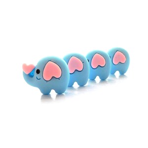 May include: Four blue elephant figurines with pink heart-shaped ears and a pink heart-shaped trunk. The elephants are arranged in a line, facing the same direction.