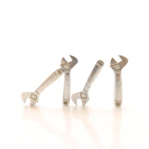 May include: Three silver adjustable wrenches are arranged in a row on a white background. The wrenches are positioned so that they appear to be walking.