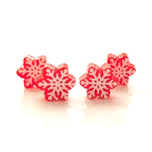 May include: Four red snowflake-shaped ornaments with white details.
