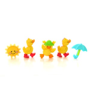 May include: A set of five yellow duck and sun-shaped buttons with red, green, and blue accents. The ducks are wearing red boots and a green hat. The sun has a smiling face. The set also includes a blue umbrella.