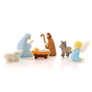 May include: A nativity scene set with a blue-robed Mary, a brown-robed Joseph, a baby Jesus in a manger, a white lamb, a donkey, and an angel with wings.