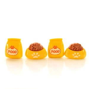 May include: Four miniature yellow pet food bowls with a paw print design and the word "FOOD" printed on the front. Two bowls are filled with brown pet food.