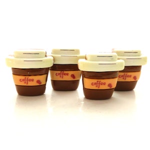 May include: Four miniature ceramic coffee cups with brown and white lids and the word "coffee" printed on the front in red.