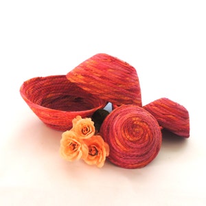 May include: Four woven baskets in shades of red and orange with a cluster of peach-colored roses.