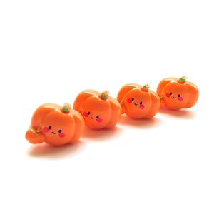 May include: Four small orange pumpkins with cute faces, each with a green stem. The pumpkins are arranged in a row on a white background.