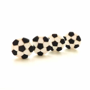 May include: Four soccer ball-shaped decorative knobs. Each knob features a classic black and white pentagon pattern, resembling a soccer ball. The knobs are arranged in a diagonal line against a white background, suitable for sports-themed decor.