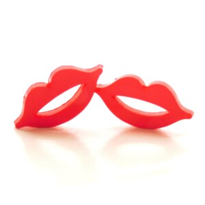 May include: A pair of red plastic lips, shaped like a mustache, for a party or costume.