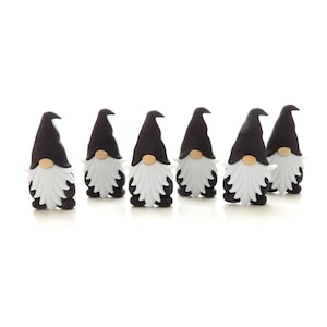 May include: Six black and white gnome figurines with white beards and black hats. The gnomes are standing in a row on a white background.