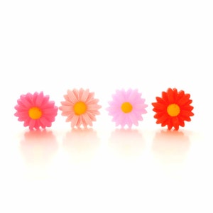 May include: Four plastic flower embellishments in a row. The flowers are pink, light pink, purple, and red. The flowers have yellow centers.